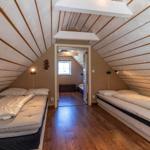 Zwei Betten in einem Dachzimmer mit Holzdecke und -boden.