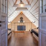 Dachgeschosszimmer mit Holzboden, Bett und Fernseher