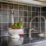 Küchenzeile mit Spüle, Wasserhahn und Schale mit Gemüse.