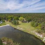 Liegenschaft mit See, Booten und Wald. Mehrere Häuser und ein Fußballtor sind sichtbar.