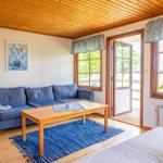 Ein Wohnzimmer mit blauem Sofa, Holztisch und blauem Teppich. Durchgang zur Terrasse.