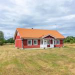 Rotes Holzhaus mit orangefarbenem Dach auf grünem Feld