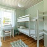 Zimmer mit Doppelstockbett, Schreibtisch und Fenster.