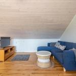 Ein Wohnzimmer mit blauem Sofa, Holzboden und schrägen Holzwänden.