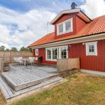Rotes Holzhaus mit Terrasse, Grill und Garten.