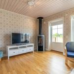 Wohnzimmer mit Holzboden, Fernseher, Kamin und blauem Sessel.