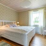 Schlafzimmer mit Bett, Stuhl und Fenster. Wände mit Tapete, Holzboden und Decke.