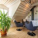 Wohnbereich mit Sitzgruppe, Pflanze und Holzwand. Holzdecke und Boden.
