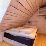 Schlafzimmer mit Dachschrägen, Bett, Kleiderständer und Holzwand.