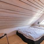 Schlafzimmer mit Dachschrägen, Bett, Stuhl und Kleiderhaken.