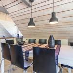 Essbereich mit Tisch, Stühlen und Küchenzeile unter Holzdecke.