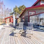Holzterrasse mit zwei Liegestühlen und Glasfront zum Haus.