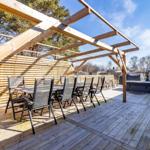 Holzterrasse mit Pavillon, Sitzgruppe und Whirlpool im Freien.