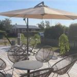 Terrasse mit Tisch, Stühlen und Sonnenschirm. Hintergrund: Garten und Nachbarhaus.