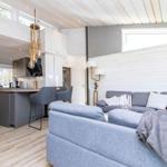 Wohn- und Küchenbereich mit grauem Sofa, Holzboden und hohem Dach.