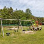 Kinderbereich mit Schaukel, Sandkasten und Spielplatz.