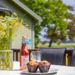 Auf der Terrasse steht ein Tisch mit Blumen, Muffins und einem Getränk.