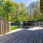 Holzterrasse mit Sitzgruppe, Blick auf grünen Rasen und Wald.