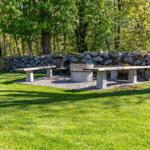 Hölzerne Bank und Tisch im Garten neben Steinmauer und Hängemöbel.