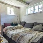 Schlafzimmer mit Sofa-Bett, Fenstern und Holzwänden.