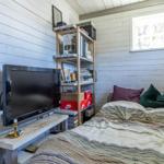 Schlafzimmer mit Bett, Fernseher und Bücherregal an der Wand.