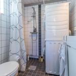 Badezimmer mit Dusche, Waschmaschine und Toilette.