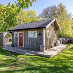 Holzhaus mit roter Tür und Holzveranda im Grünen