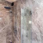 Duschkabine mit Glaswand und Duschkopf an der Wand