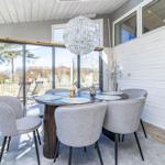 Essbereich mit runder Tisch, grauen Stühlen und Glasfront zur Terrasse.
