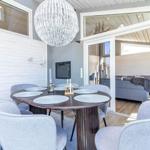 Essbereich mit runden Tisch und Stühlen, Glaswand zum Wohnzimmer, Deckenleuchte.