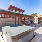 Haus mit Whirlpool, Terrasse und Sitzgelegenheiten im Freien.