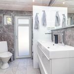 Badezimmer mit Toilette, Waschbecken und Dusche. Wandverkleidung aus Stein.