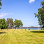 Grünes Feld mit Fußballtoren am See. Menschen spielen im Freien.