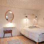 Schlafzimmer mit Doppelbett, Krippe, Spiegel und Wandregal.