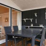 Terrasse mit Tisch und Stühlen, schwarze Wand und Glasfront zum Innenraum.