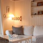 Wohnzimmer mit Sofa, Glas-Tisch und Wandregal. Fensterblick auf Wald.