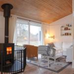 Wohnzimmer mit Kamin, Sofa, Sessel und großem Fenster. Holzdecke und -boden.