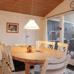 Essbereich mit runden Tisch und Stühlen, Glasfront zum Balkon, Holzdecke und Wand.