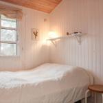 Ein Schlafzimmer mit Bett, Fenster und Wandregal.