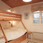 Zimmer mit Doppelstockbett, Fenster und Holzwandverkleidung.