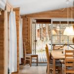 Esszimmer mit Holztisch, Stühlen und Blick auf Terrasse.