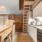 Küche mit Holzoberflächen, Kühlschrank, Herd und Treppe zum Dachboden.