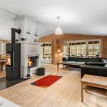 Wohn- und Essbereich mit Kamin, Holzwand und schwarzen Sofas.