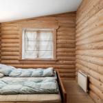 Schlafzimmer mit Holzwand, Bett und Fenster