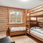 Zimmer mit Holzwand, Doppelstockbett und Fenster mit Blick nach draußen.