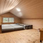 Schlafzimmer mit Holzwand, Bett und Fenster