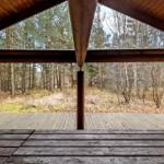 Holzterrasse mit Blick in den Wald. Sichtbar sind Bäume und Unterholz.