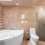 Badezimmer mit Whirlpool, Toilette und Dusche. Holzwand und Fliesen.