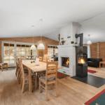 Esszimmer mit Holztisch, Kamin und Sitzbereich. Holzwände und -boden.