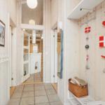 Hallway with wooden walls, coat rack, and Danish flags on the wall.
